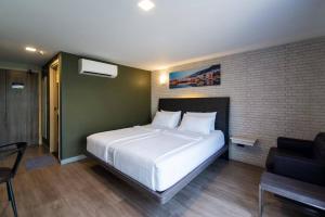 a bedroom with a large white bed and a chair at BB Glass House Pattanakrn บีบี กลาสเฮ้าส์ พัฒนาการ in Bangkok