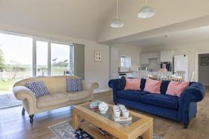 a living room with two blue couches and a table at Coldwells Farmhouse in Dalkeith
