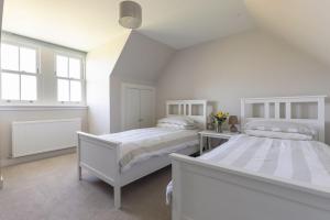 two beds in a bedroom with white walls and windows at Coldwells Farmhouse in Dalkeith