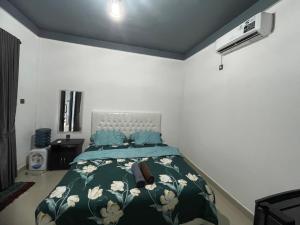 a bedroom with a bed with a green comforter at AFWA Surf and Stay in Selong Belanak
