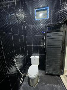 a bathroom with a toilet and a black tiled wall at AFWA Surf and Stay in Selong Belanak