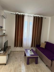 a living room with a purple couch and a table at Il Sol Apartment in Lezhë