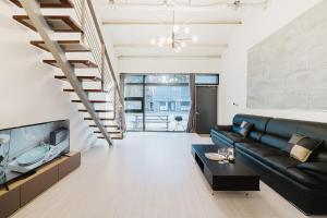 a living room with a black leather couch and a tv at Sokcho Night Sky Pension in Sokcho
