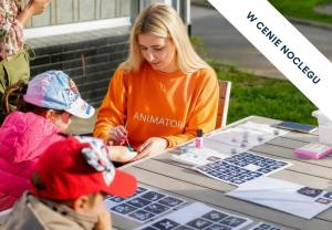 a woman sitting at a table with two children playing at Prawdzic Family Resort & Wellness in Gdańsk