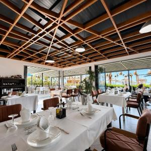 a restaurant with white tables and chairs and windows at OKEJ Hotel in Golem
