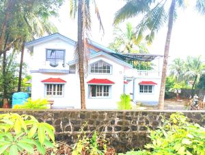 a white house with palm trees in front of it at Peace Villa with pool in Murud