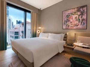 a bedroom with a large white bed and a large window at Mondrian Singapore Duxton in Singapore +77 photos