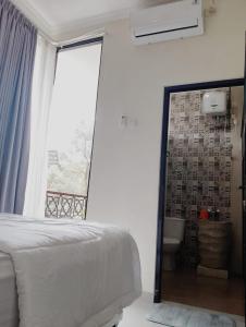 a bedroom with a bed and a bathroom with a window at A-Three Guest House in Malang