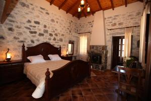 a bedroom with a bed and a stone wall at Vasilios Apartments Hotel in Limeni