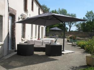 a patio with an umbrella and a couch and chairs at CAMPAGNE et FORET in Coulours