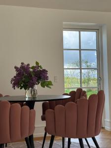 a dining room table with chairs and a vase with purple flowers at Estate in calm nature in Sorø +17 photos