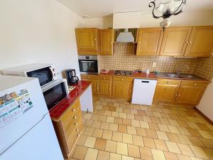 a kitchen with wooden cabinets and a white refrigerator at La Villa Santranges in Châtillon-sur-Loire