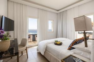 a white bedroom with a bed and a desk and window at Casa Kiku Mykonos in Mikonos