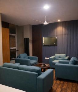 a living room with blue couches and a flat screen tv at Cassette Inn in Zahirābād