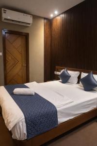 a bedroom with a large white bed with blue pillows at Cassette Inn in Zahirābād