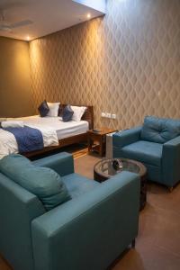 a bedroom with a bed and a couch and chairs at Cassette Inn in Zahirābād