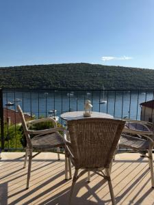 a table and chairs on a deck with a view of the water at White stone house in Bigova