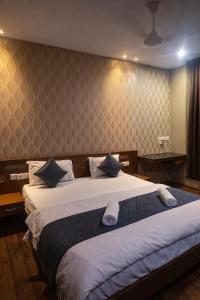 a bedroom with a large bed with white sheets at Cassette Inn in Zahirābād +6 photos