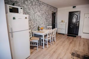 a kitchen with a white refrigerator and a table with chairs at The Home in Gheorgheni