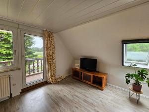 a living room with a flat screen tv and two windows at Ferienwohnung "Haggi" 35672 in Uplengen