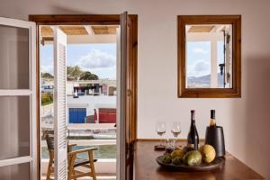 a table with a bowl of fruit and wine glasses at Infinito Boathouse Milos in Agia Irini Milos +20 photos