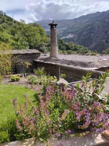 a garden with flowers and a stone house at Cortijo De Los Abuelos in Pampaneira +7 photos