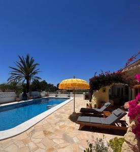 a swimming pool with an umbrella and chairs next to a house at Villa Mirella in Jávea