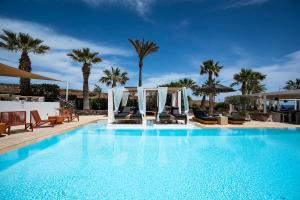 a large swimming pool with chairs and palm trees at Aurora Luxury Suites in Imerovigli