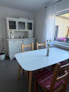 a white dining room table with chairs and a kitchen at Schlosserhäuschen in Leipzig