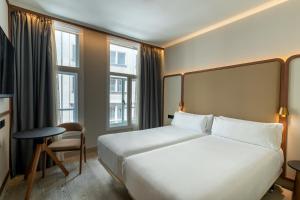 a hotel room with a large bed and windows at Petit Palace Alcalá in Madrid +91 photos