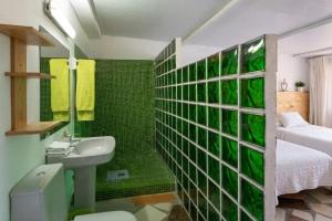 a bathroom with a sink and a green tiled wall at Jacaranda in Cádiz