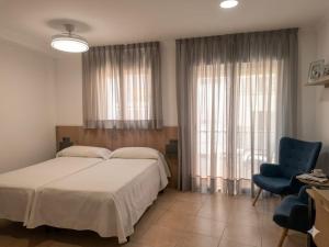 a bedroom with a bed and a blue chair at Apartamentos El Barrio in Nerja