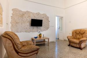 a living room with two chairs and a tv on a wall at Trullo Petronella in Cisternino