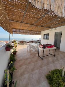 a patio with a table and chairs and a view of the ocean at Atlantic view Tamraght 2 in Tamraght Ou Fella