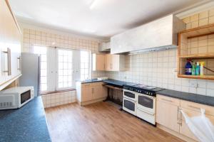 a large kitchen with white appliances and wooden floors at Room 2 - Brookvale Guest House in Southampton