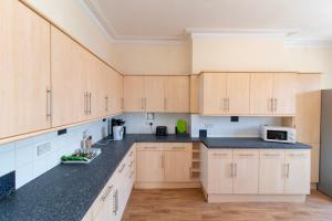 a kitchen with wooden cabinets and black counter tops at Room 2 - Brookvale Guest House in Southampton