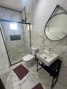 a bathroom with a sink and a toilet and a mirror at Pousada Central Araquari in Araquari