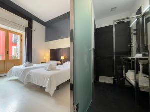 a bedroom with two beds and a glass shower at Alhambra Suites in Madrid