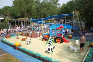 a childrens park with a playground with toys and people at Leuke 6 persoons stacaravan op top locatie! in Hoenderloo