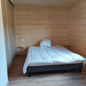 a small room with a bed in a wooden room at Chalet Les Noisetiers in Rochesson +14 photos