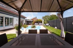 a patio with a table and chairs and a pool at Villa Béatrice - Piscine in Hochfelden