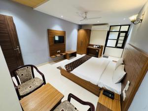 a bedroom with a bed and a table and a chair at La Casa Residency in Lucknow