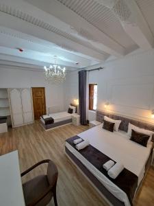 a large white room with two beds and a chandelier at Nabibek boutique in Bukhara +96 photos