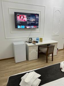 a bedroom with a desk and a tv on the wall at Nabibek boutique in Bukhara