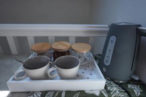 a white box with two cups and wooden stools at Steps to the Sand in Melcombe Regis +6 photos