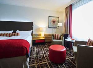 a hotel room with a bed and a red stool at City Best Autobahnhotel Stolper Heide in Berlin