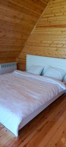 a bedroom with a white bed with a wooden ceiling at Shahdag A-Frame in Qusar