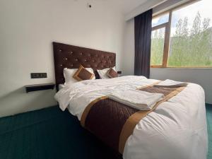 a bedroom with a large bed with a large window at Natures View Residency in Hundar +14 photos
