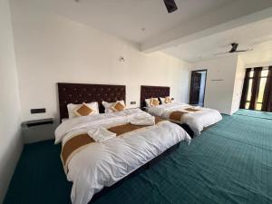 two beds in a room with green carpet at Natures View Residency in Hundar