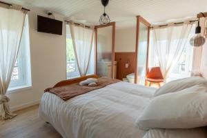 ein Schlafzimmer mit einem großen weißen Bett und einem Fernseher in der Unterkunft Le Zigzag in Retournac